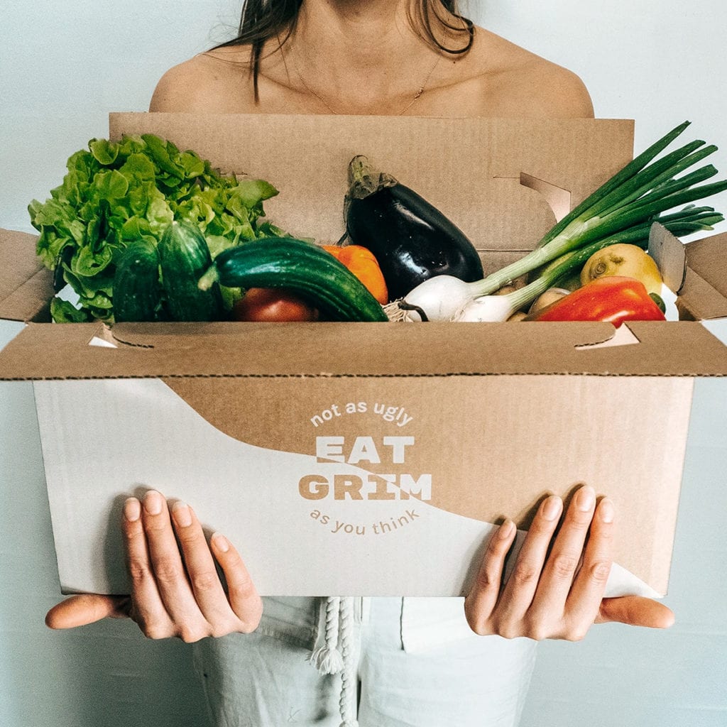Girl standing with a sustainable veggie box from Eat Grim